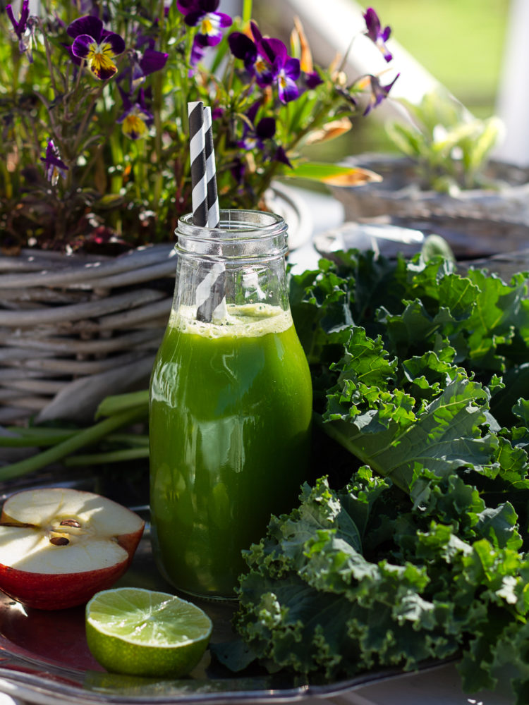 Grönkålsjuice i glaskflaska med randigt sugrör. Kale juice in a glass bottle.