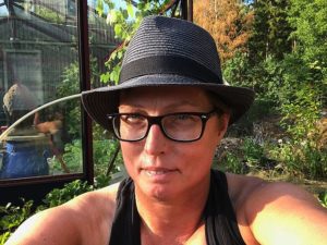 En selfie på kvinna i hatt i en trädgård.