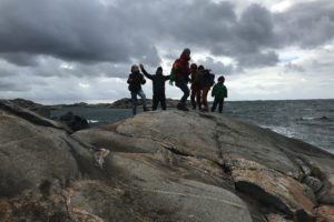 En hop människor står på en klippa med havet i bakgrunden.