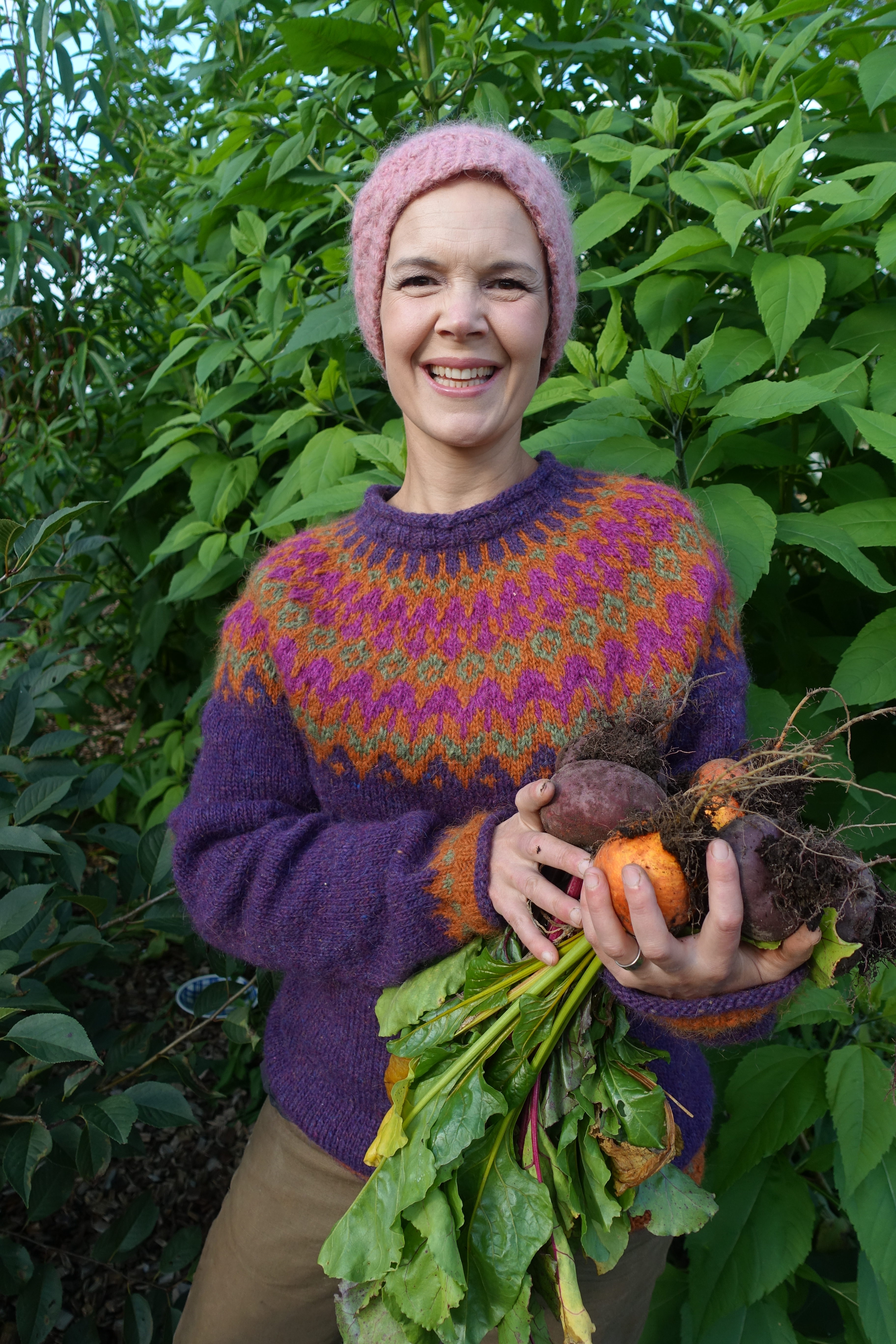 Sara står med färgranna betor i en vacker hemstickad tröja.