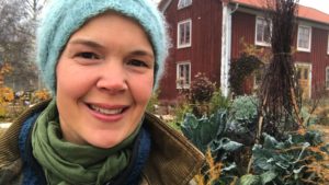 Sara Bäckmo sitter i höstiga kläder i en köksträdgård