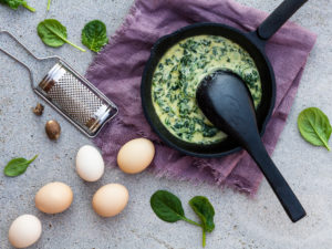 Läcker gräddstuvad spenat bredvid ett par ägg.