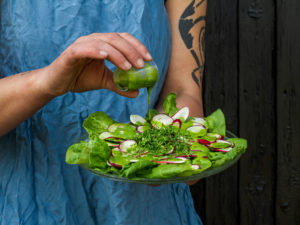 En fin sallad med rädisa och spenat, som Sara häller dressing över.