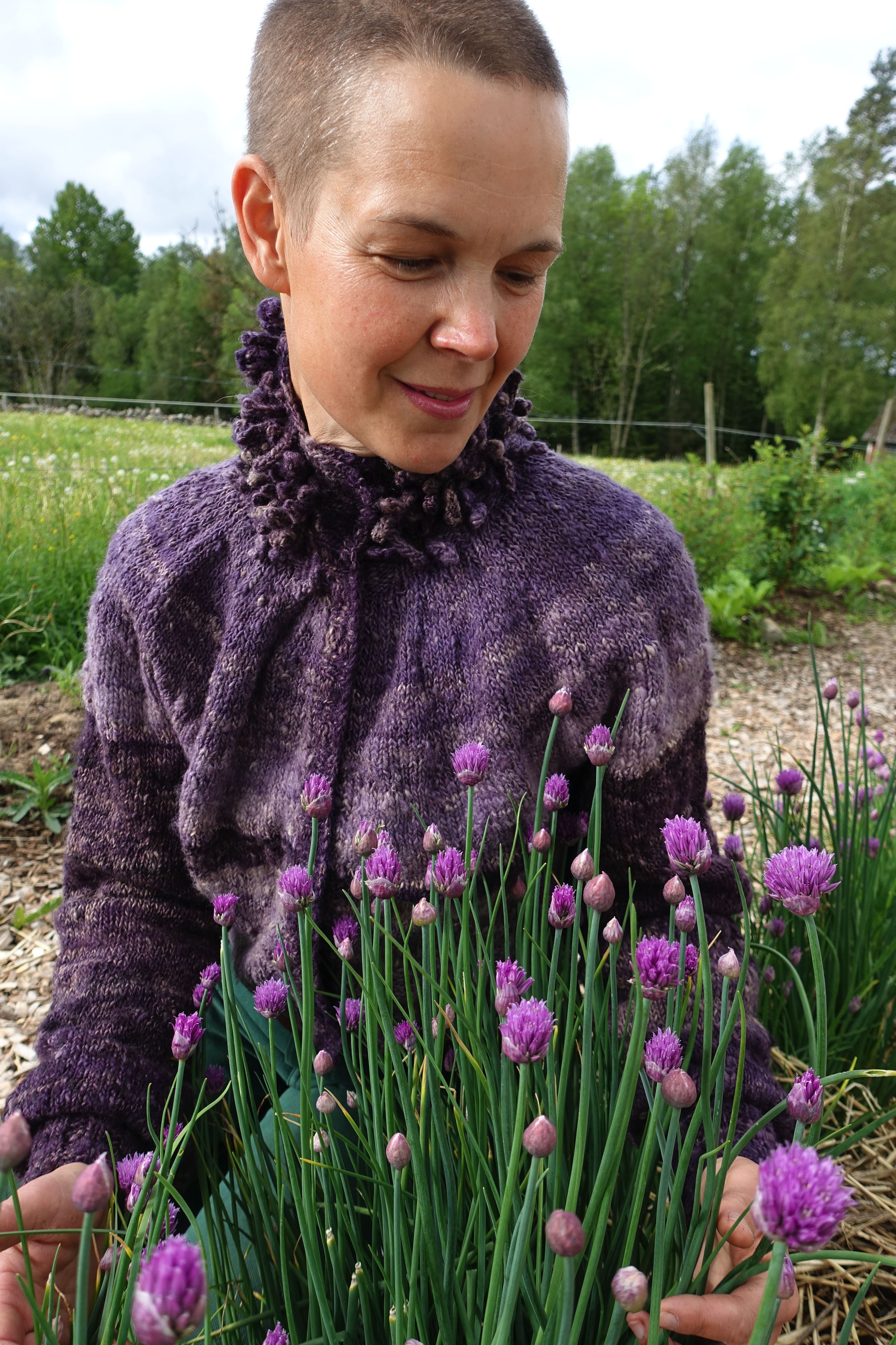 Sara sitter vid blommande gräslök. My puff sleeve cardigan.