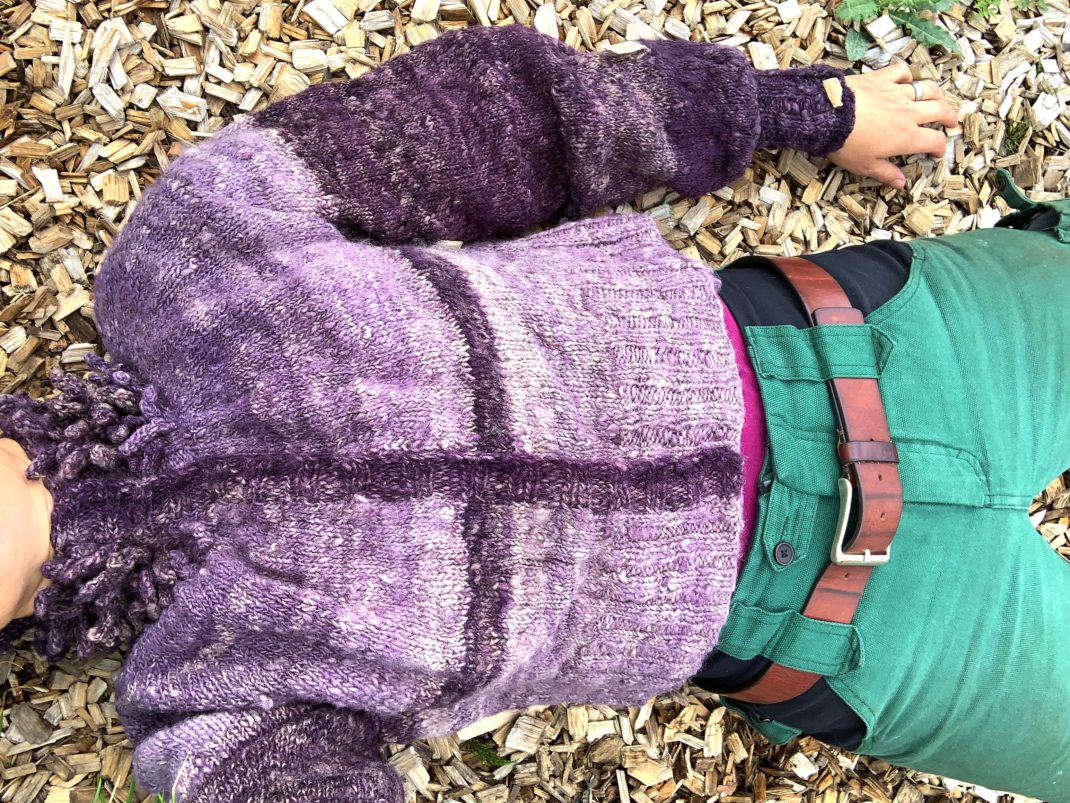 Sara ligger på träflis och hela tröjan syns. My puff sleeve cardigan. 