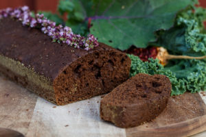 En saftig mörkbrun chokladkaka ligger på ett bord bredvid grönkål.