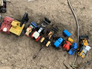 Leksaksbilar uppställda på rad i sandlådan.