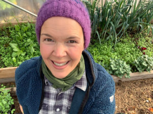 En glad Sara i ett grönt prunkande tunnelväxthus