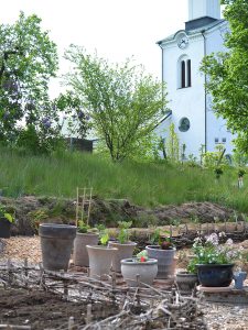 En köksträdgård med täckodlade bäddar och krukor